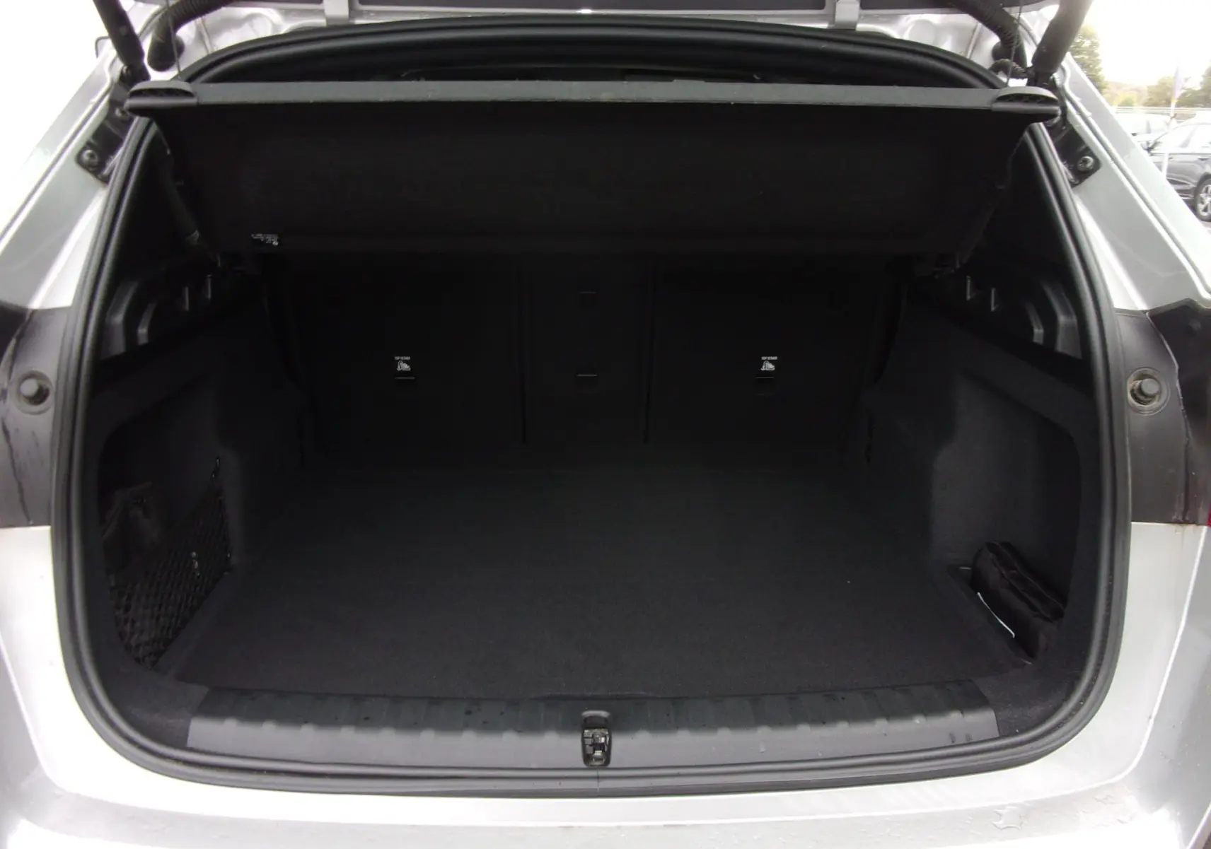 Coffre ouvert vu de l'arrière d'un BMW X1 argent métallisé 2024, montrant un espace de chargement propre et spacieux.