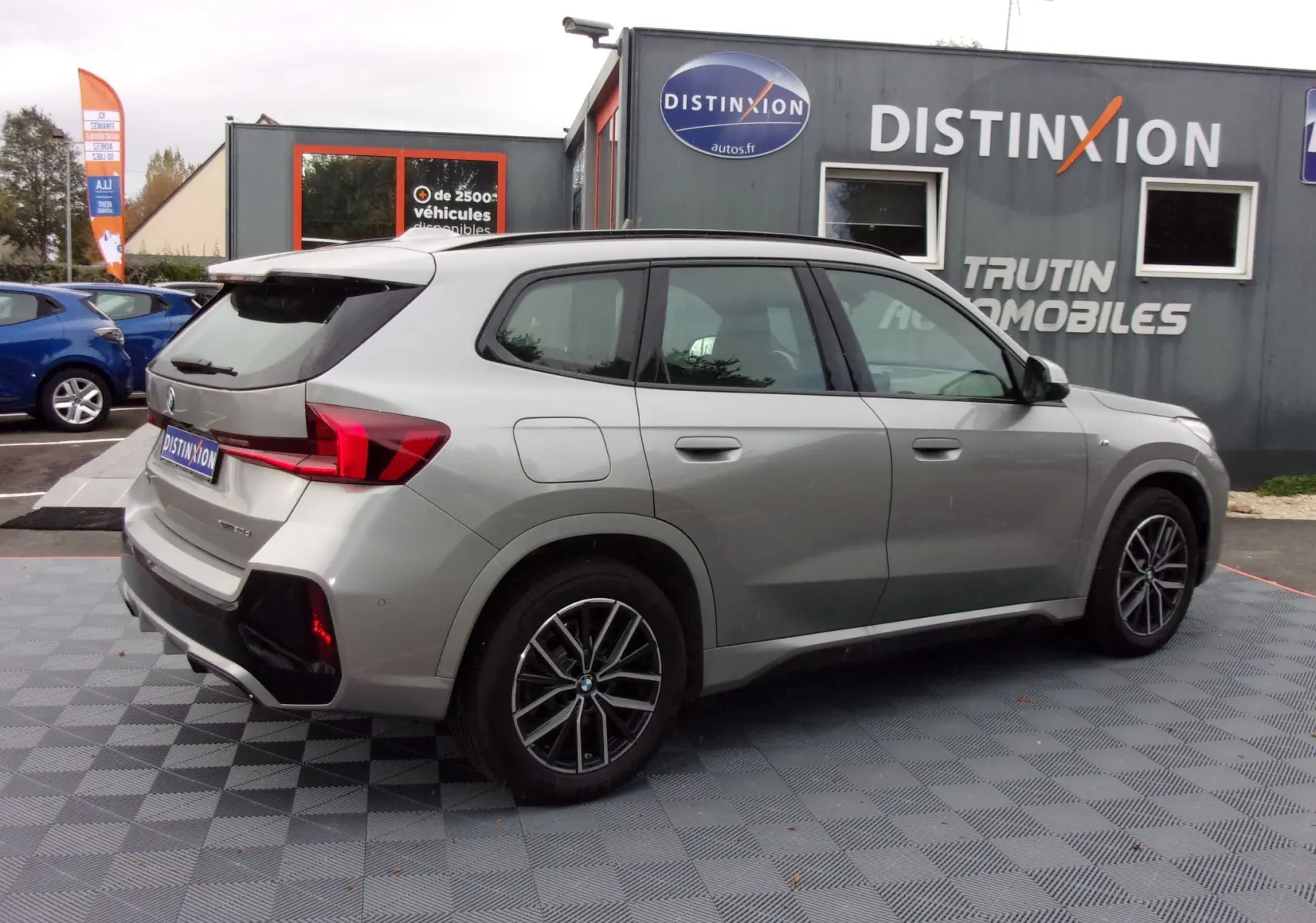 BMW X1 M Sport 2024 argent métallisé vue 3/4 arrière côté droit, avec jantes alliage et feux arrière LED distinctifs.