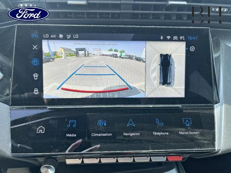 Écran tactile intérieur montrant la caméra de recul et vue 360° d'une Peugeot 308 SW blanche Okénite, version 2023 PHEV.