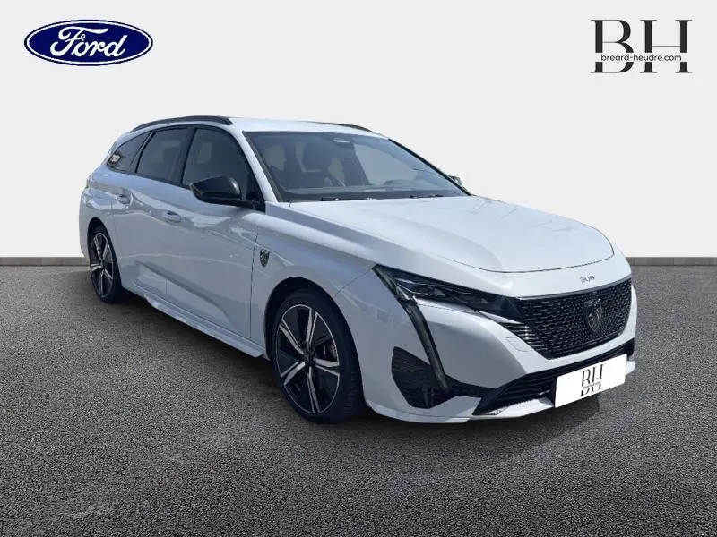 Peugeot 308 SW PHEV blanc Okénite vue 3/4 avant droit avec calandre noire et jantes alliage noires.