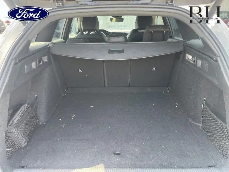 Coffre spacieux et vide vu de l'arrière d'un break PEUGEOT 308 SW blanc Okénite avec cache-bagages noir.