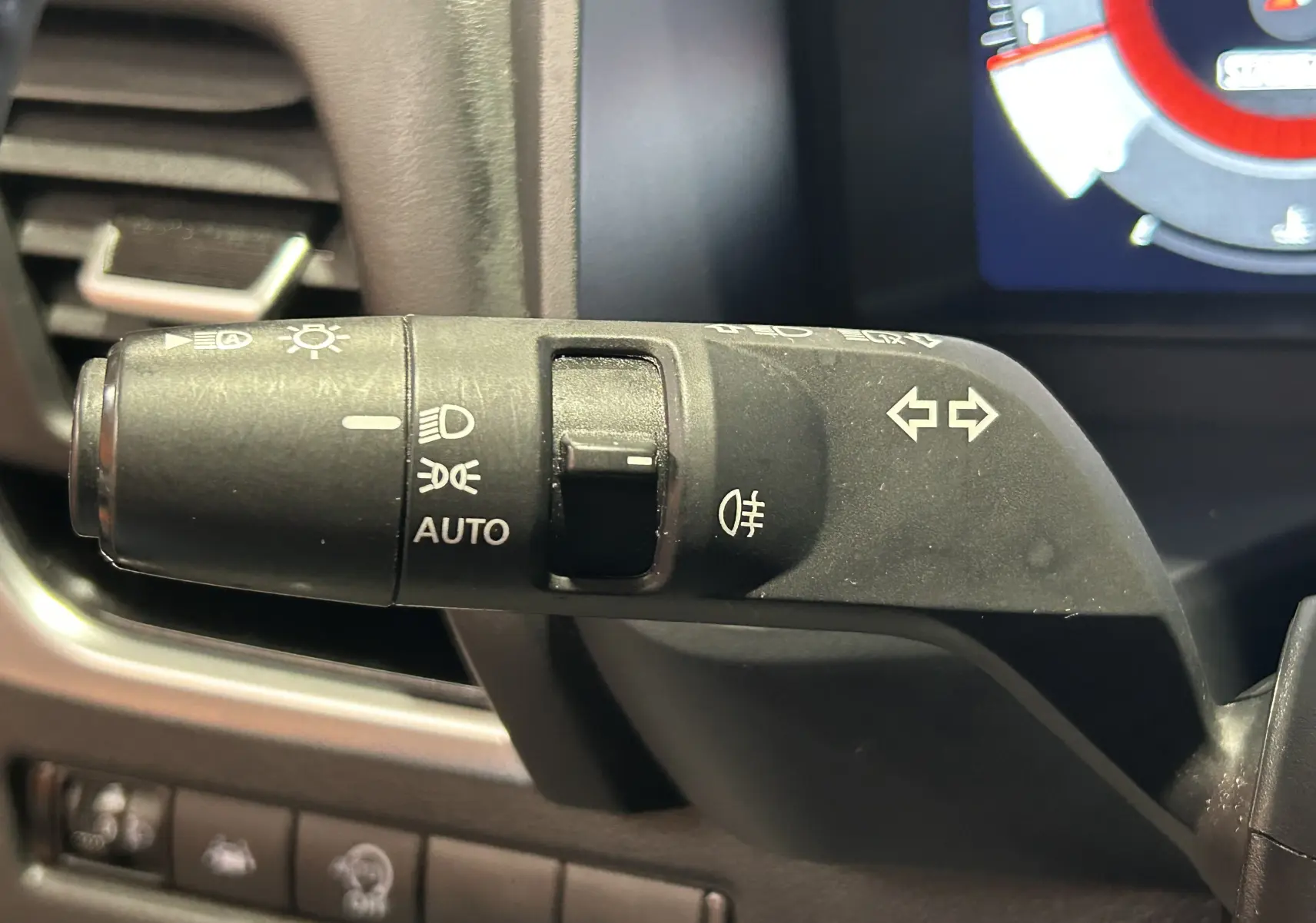 Gros plan sur la commande des phares et clignotants du Nissan Qashqai 1.3 Hybrid blanc lunaire, intérieur noir.