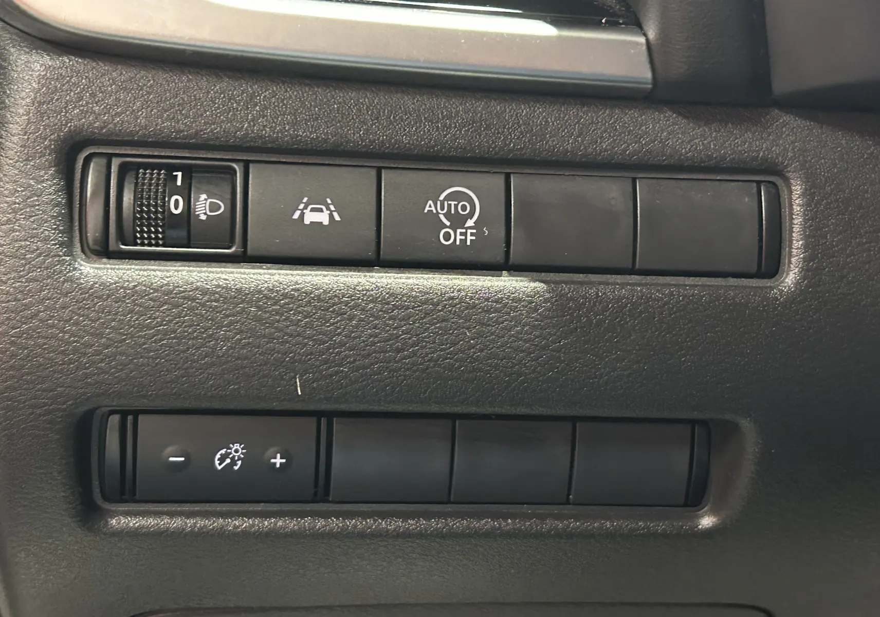 Détail des commandes intérieures du Nissan Qashqai 1.3 Hybrid 140 N-Connecta, boutons de réglage d’éclairage et d’assistance.