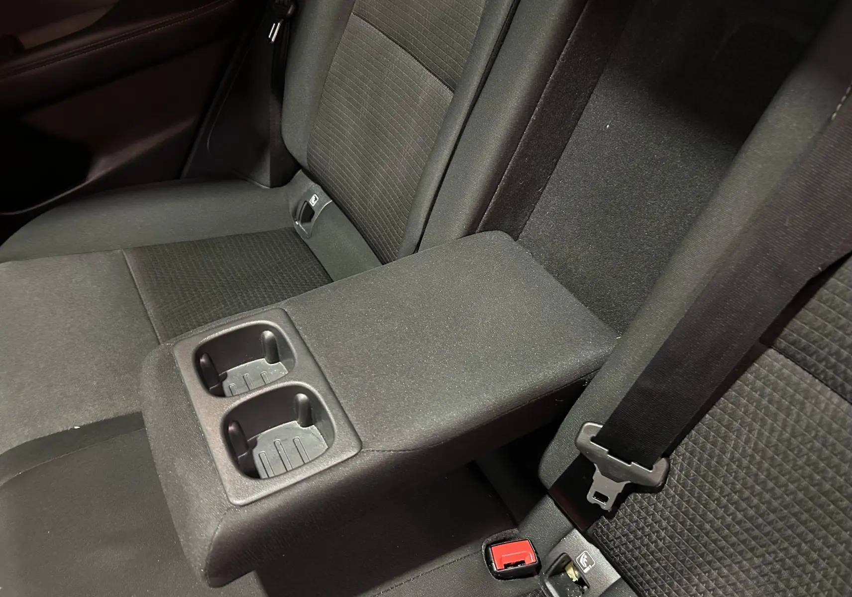 Vue rapprochée de l'accoudoir central arrière avec porte-gobelets du Nissan Qashqai 1.3 Hybrid 140 N-Connecta, intérieur tissu noir.