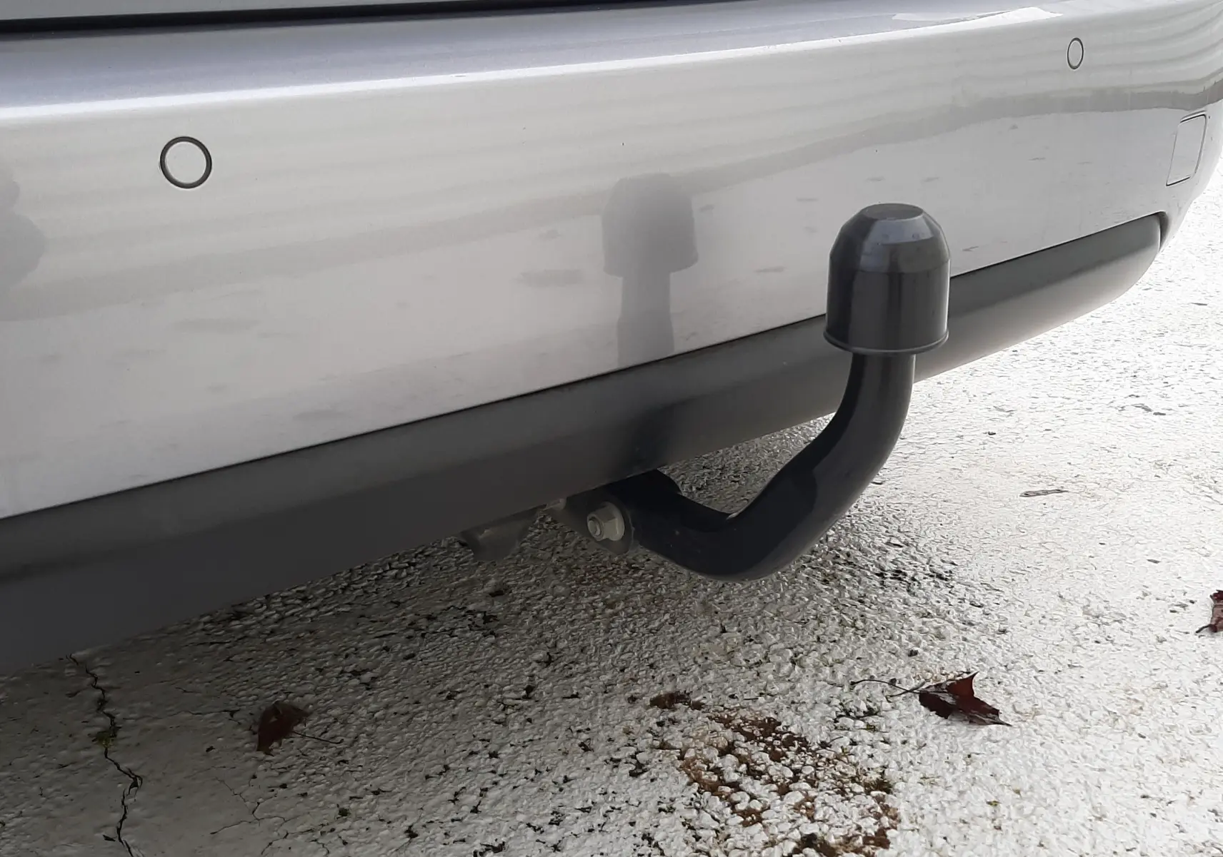 Gros plan sur l'attelage noir fixé au pare-chocs arrière gris Artense du Peugeot 308 SW 2021.