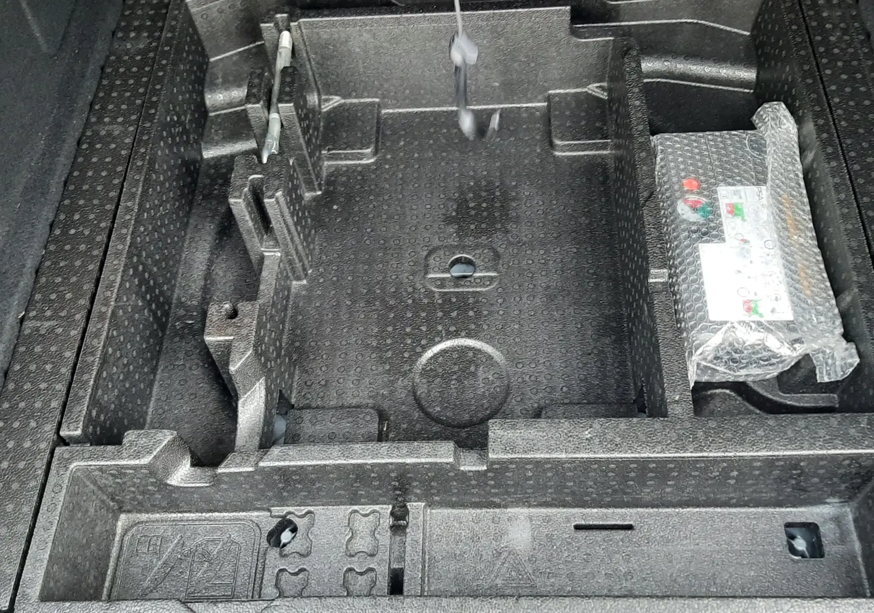 Rangement en mousse noire sous le coffre de la Peugeot 308 SW 1.2 PureTech 2021, vue plongeante sur les compartiments.