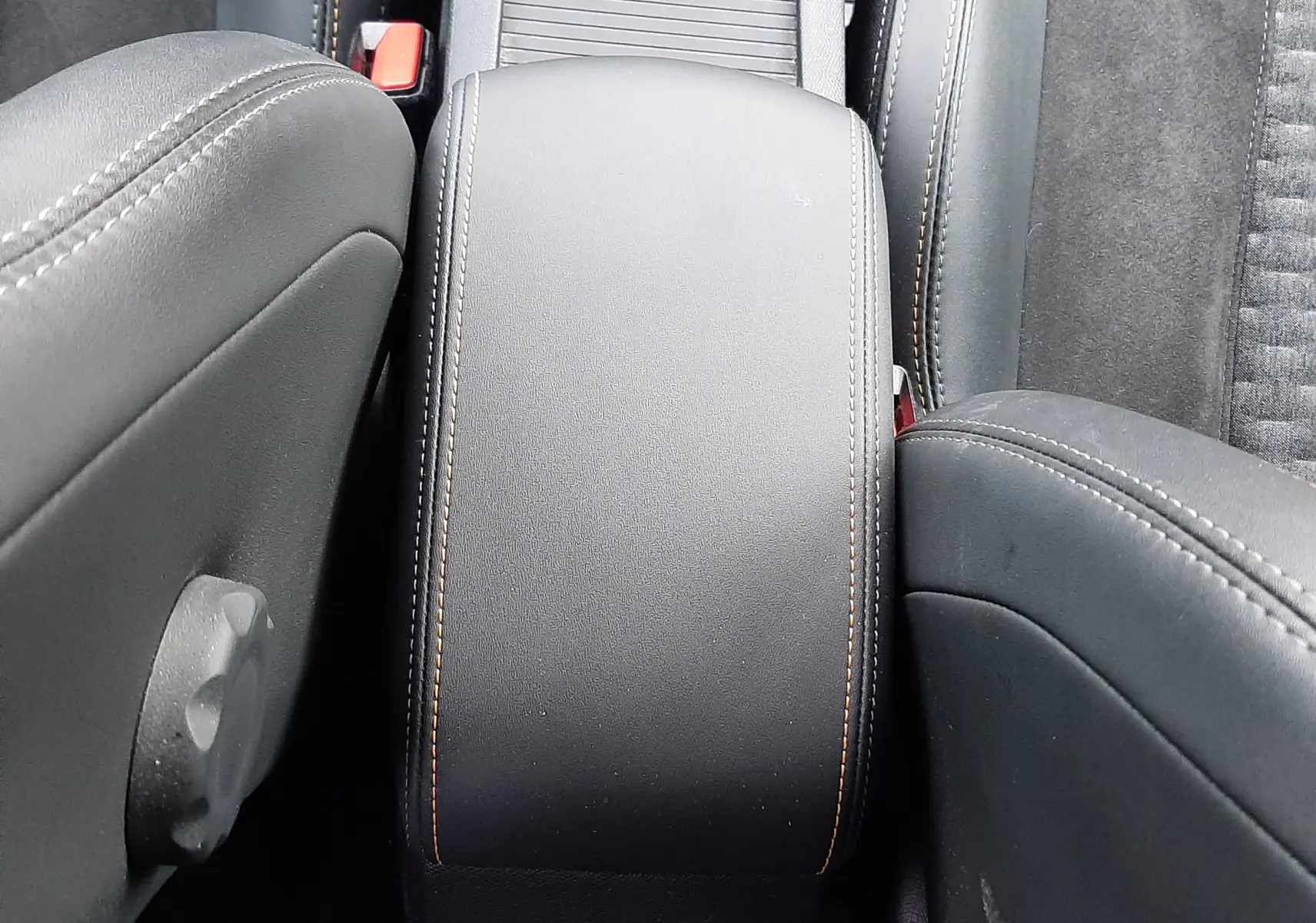 Vue plongeante sur l'accoudoir central noir avec surpiqûres contrastantes dans l'habitacle d'une Peugeot 308 SW 2021.