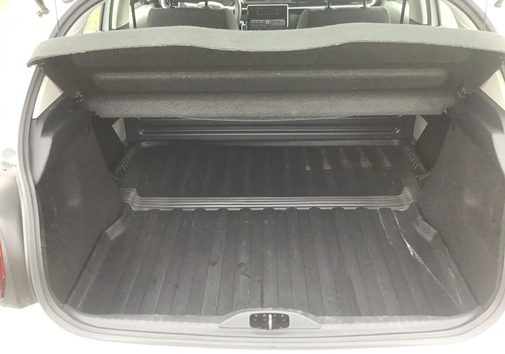 Vue arrière du coffre ouvert d'une Citroën C3 Société blanche, montrant l'espace de chargement vide et la tablette arrière relevée.