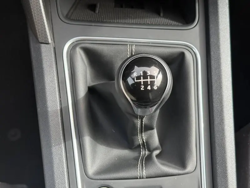 Vue rapprochée du pommeau de levier de vitesses manuel noir avec coutures blanches sur une SEAT LEON 2025.