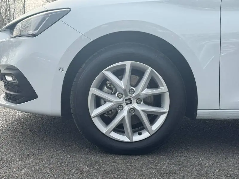 Gros plan sur la roue avant gauche blanche Nevada métallisée d’une SEAT LEON 2.0 TDI 115ch STYLE XL avec jante alu.