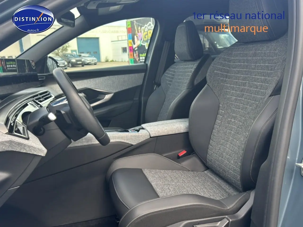 Vue intérieure côté conducteur du Peugeot 3008 2025 bleu, sièges tissu et cuir avec accoudoir central et volant multifonction.