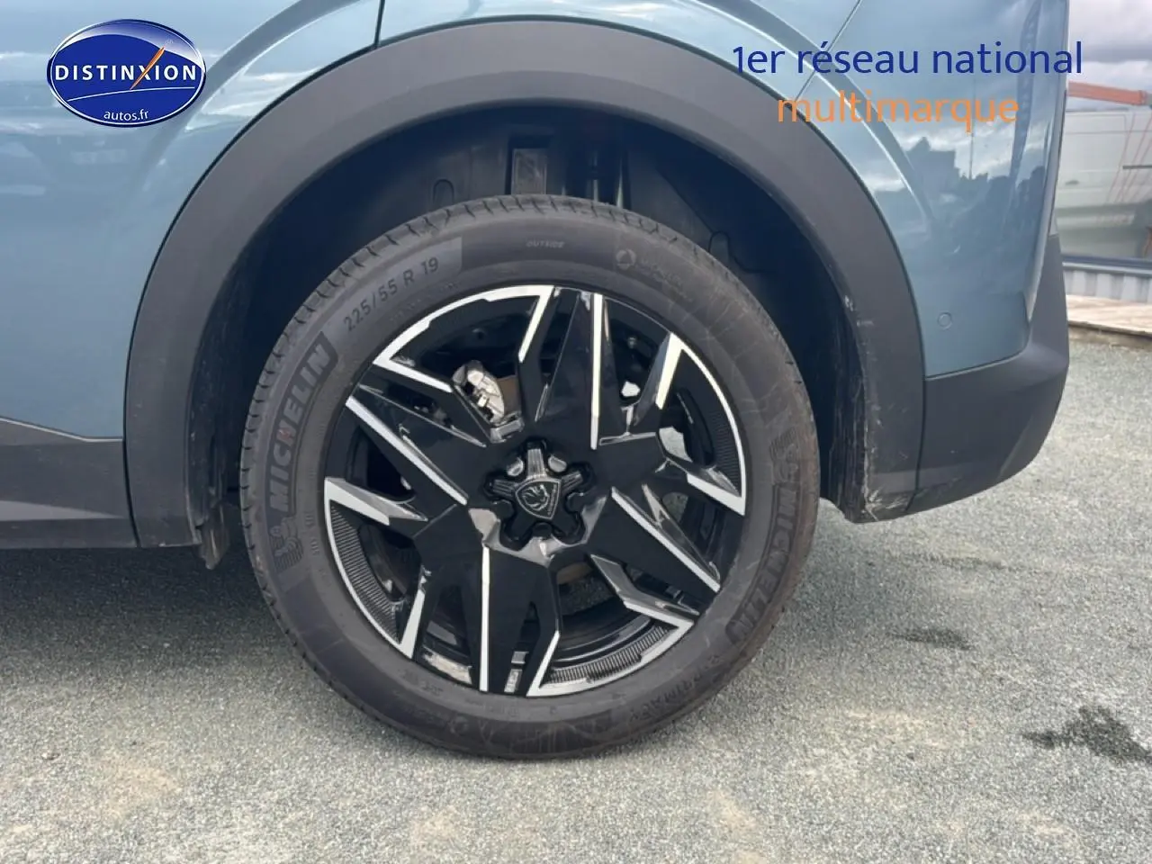 Gros plan sur la roue avant gauche avec jante alu noire et argentée du Peugeot 3008 bleu 2025.