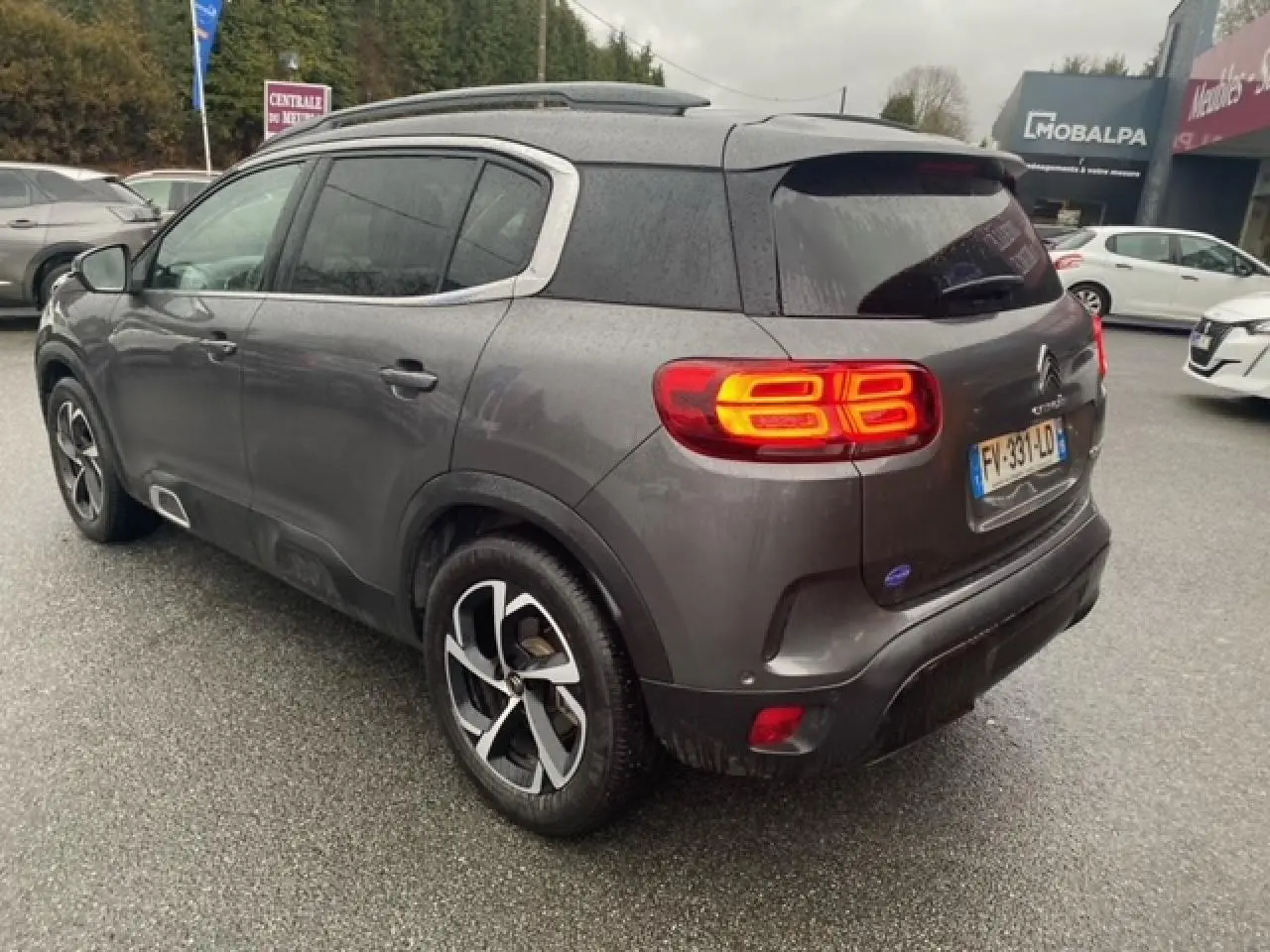 Vue 3/4 arrière droite d'un Citroën C5 Aircross gris platinium avec feux arrière allumés et jantes alliage 18 pouces.