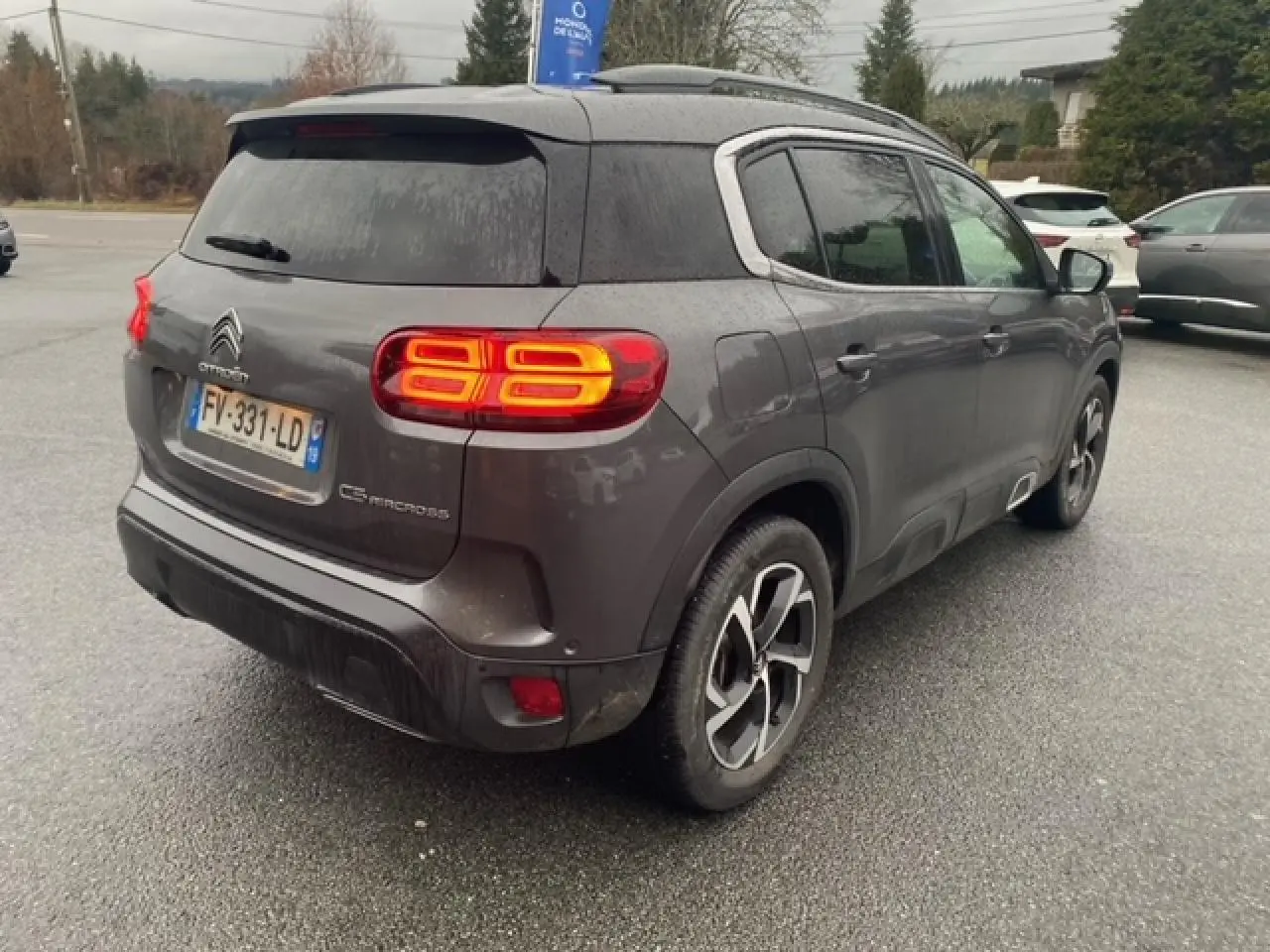 Vue 3/4 arrière droite d'un Citroën C5 Aircross gris platinium avec feux arrière allumés et jantes alliage 18 pouces.
