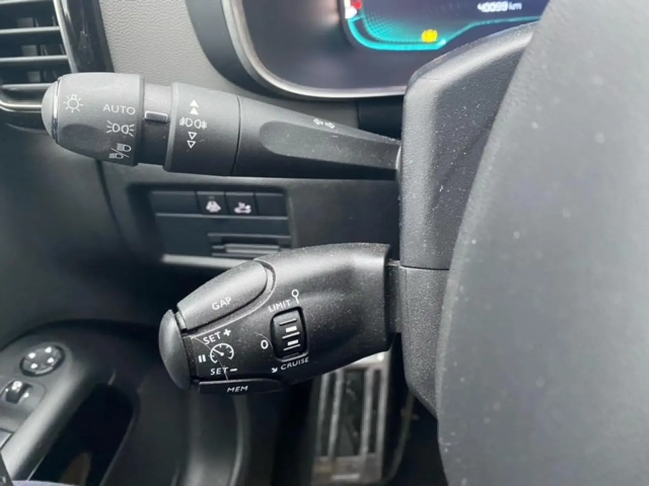 Gros plan sur les commandes au volant du Citroën C5 Aircross gris platinium, montrant les leviers de régulateur et feux.