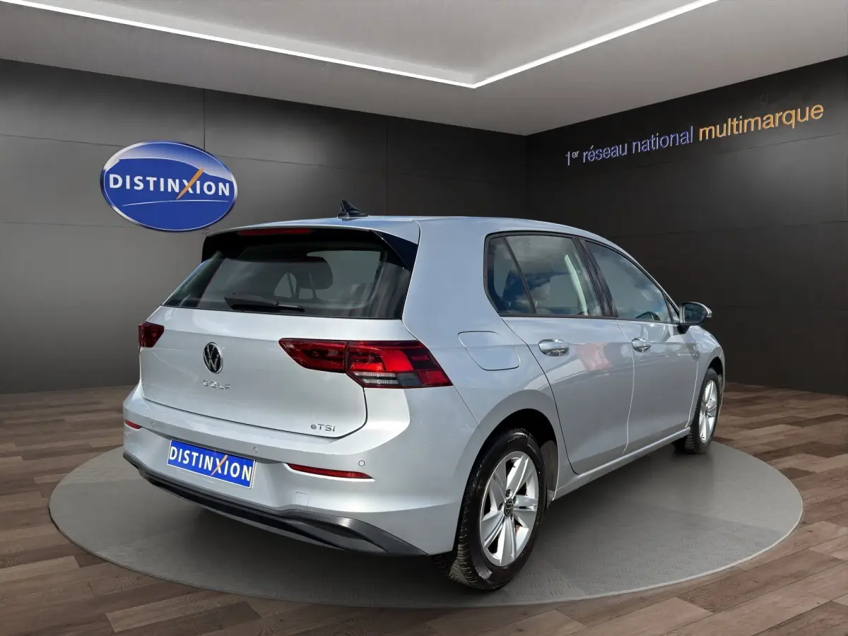 Vue 3/4 arrière droite d'une Volkswagen Golf gris clair 2022 avec feux LED et badge eTSI visible.