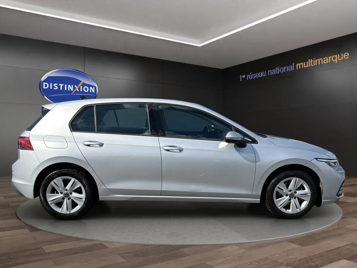 Volkswagen Golf gris clair vue de profil côté gauche dans un showroom avec jantes alliage cinq branches.