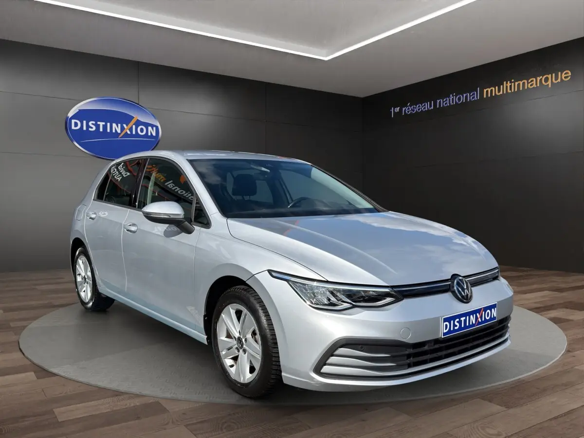 Volkswagen Golf gris clair vue 3/4 avant droit, avec phares LED et jantes alliage cinq branches.
