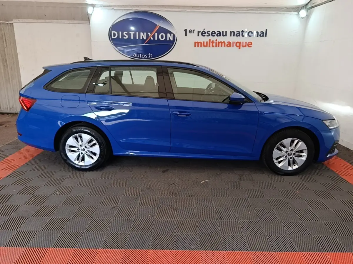 Vue de profil côté gauche d'une Skoda Octavia break bleue dans un showroom avec logo Distinxion en arrière-plan.
