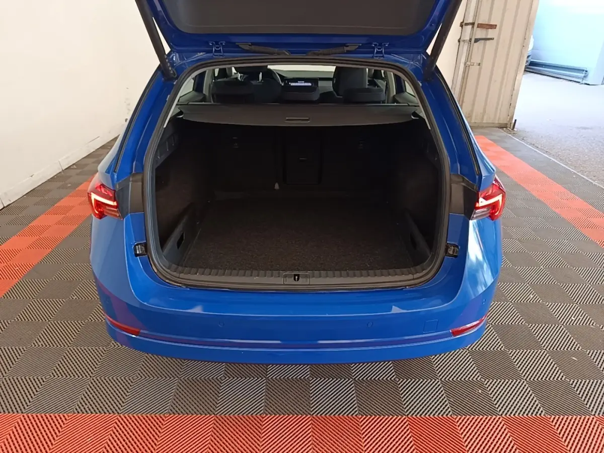 Vue arrière d’un Skoda Octavia bleu électrique 2024 avec coffre ouvert et intérieur spacieux visible.