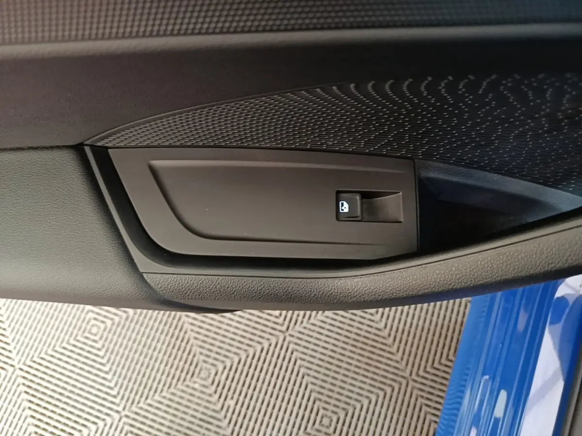 Détail de la poignée intérieure de porte côté conducteur d'une Skoda Octavia 2024 bleue avec bouton de verrouillage.