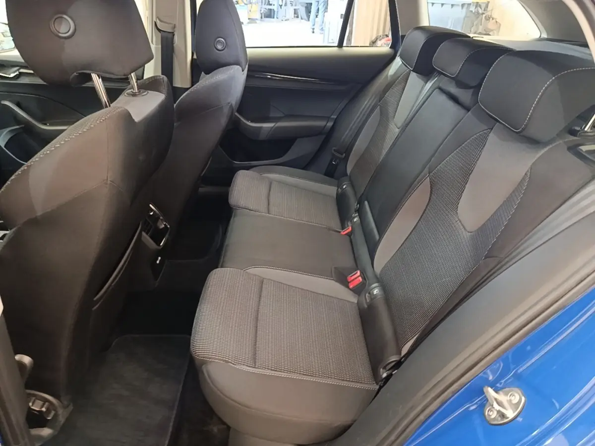 Vue intérieure côté gauche montrant la banquette arrière grise et noire de la Skoda Octavia 2024 avec porte bleue ouverte.