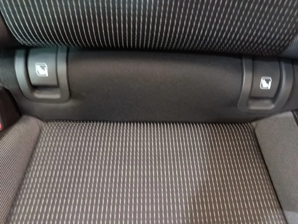 Détail de la banquette arrière grise à motifs rayés avec commandes de rabattement visibles, Skoda Octavia 2024.