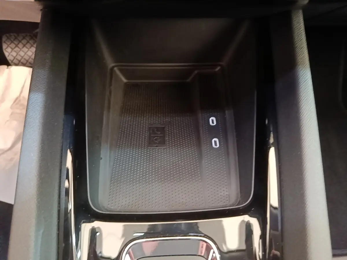 Vue rapprochée de la console centrale noire de la Skoda Octavia 2024, avec zone de recharge sans fil et ports USB visibles.
