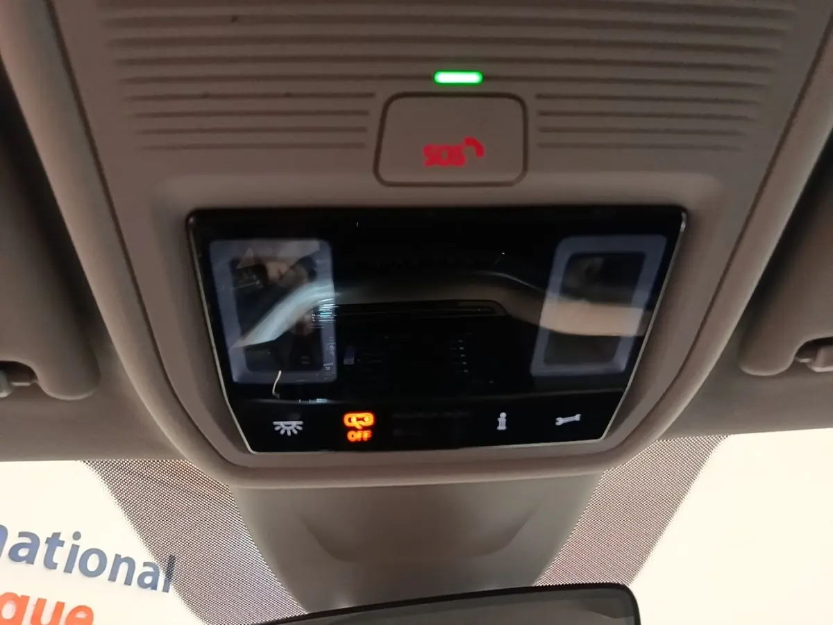 Gros plan sur le panneau de commande de toit intérieur gris avec bouton SOS rouge et éclairage tactile éteint.