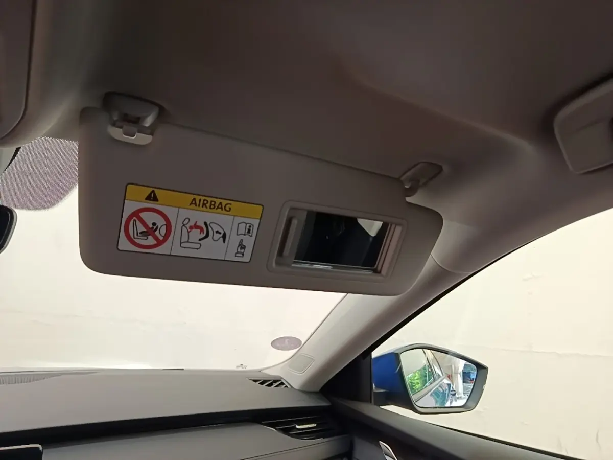 Intérieur côté passager d’une Skoda Octavia 2024, visière pare-soleil beige avec miroir et avertissement airbag visible.
