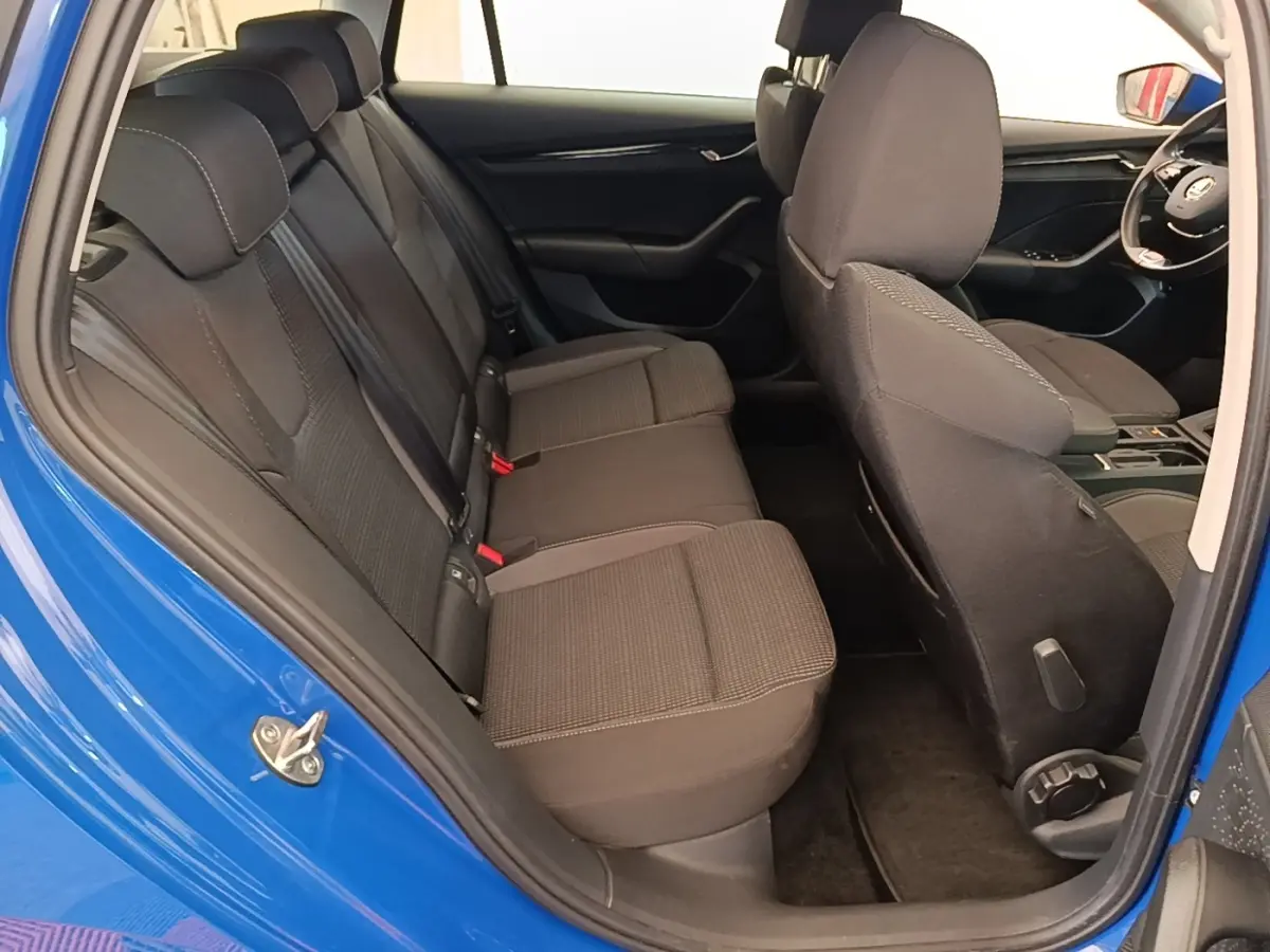 Vue intérieure côté gauche montrant la banquette arrière noire et la porte bleue ouverte d'une Skoda Octavia 2024.