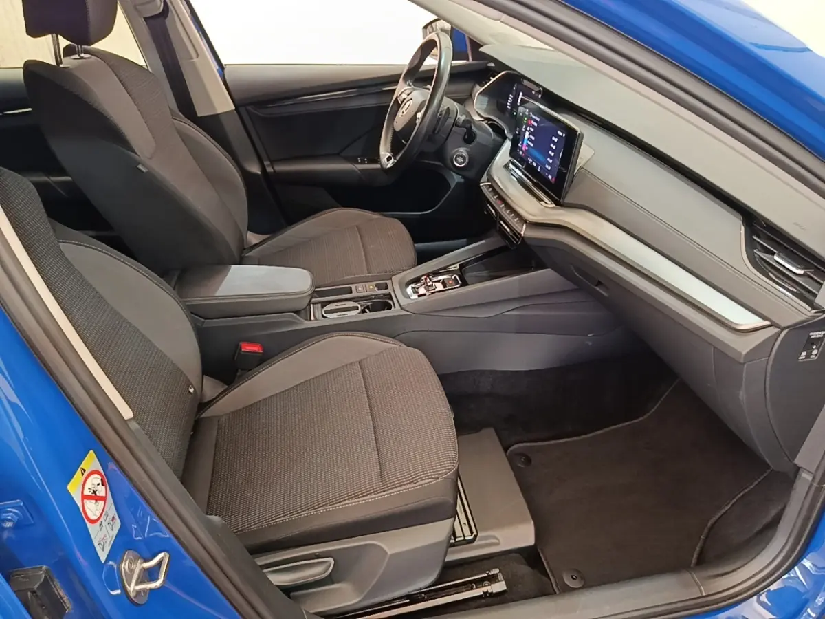 Intérieur avant droit d'une Skoda Octavia 2024 bleu, sièges tissu gris et tableau de bord avec écran tactile.