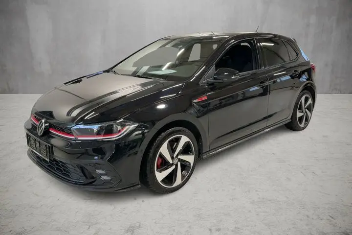 Vue 3/4 avant droite d'une Volkswagen Polo GTI noire 2024 avec jantes alliage 17 pouces et détails rouges sur la calandre.
