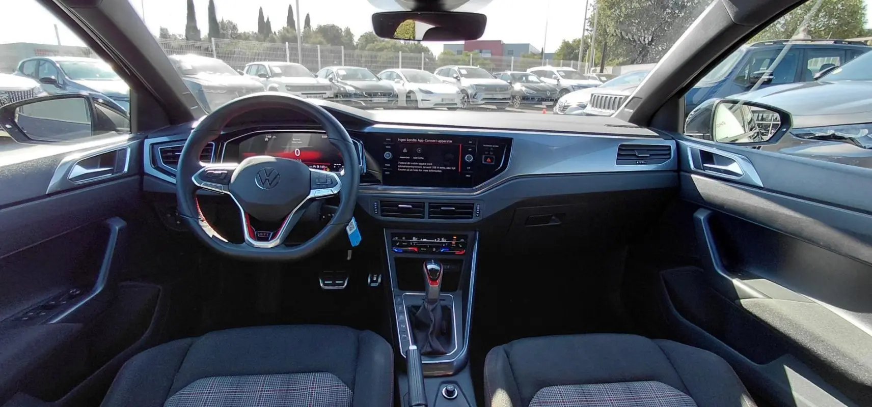 Vue intérieure avant de la Volkswagen Polo GTI 2024 noire, avec volant sport, cockpit numérique et console centrale moderne.
