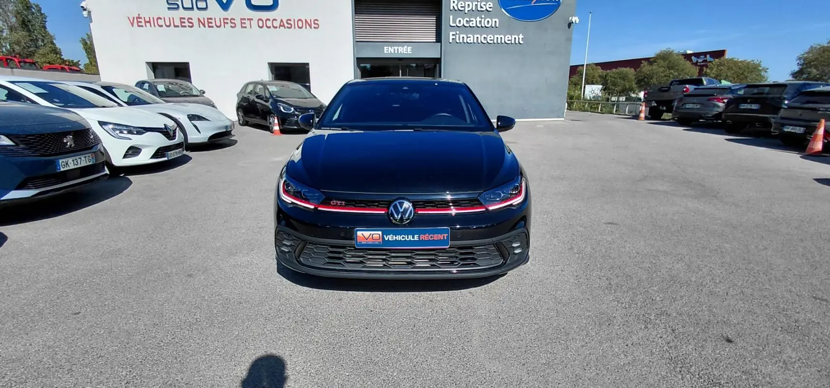 Volkswagen Polo GTI noire vue de face, avec signature lumineuse rouge et calandre sportive en concession.