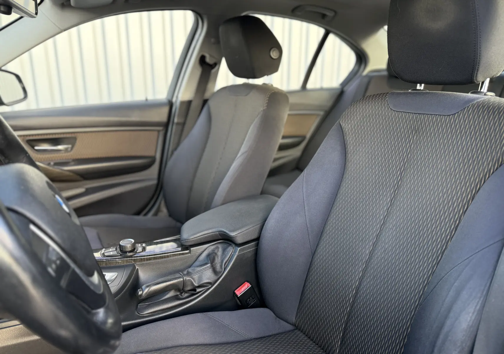 Intérieur de BMW Série 3 320D 2013, vue côté gauche sur sièges tissu gris et console centrale avec levier de vitesse.