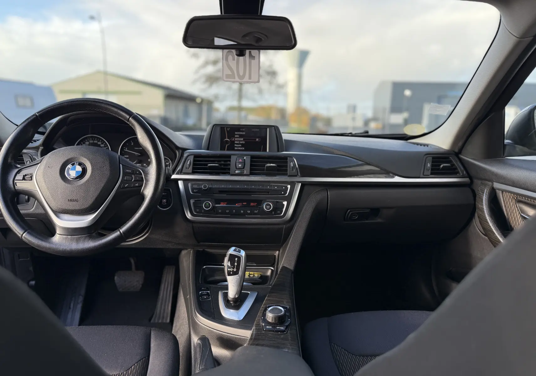 Intérieur de BMW Série 3 320D 2013 vu de face, tableau de bord noir avec console centrale et volant multifonction.