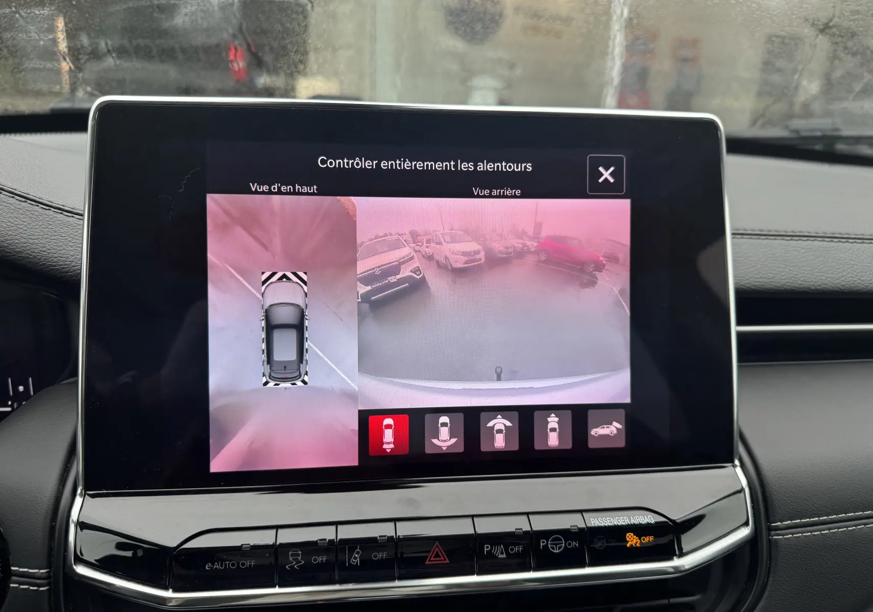 Écran central du Jeep Compass gris 2023 montrant la caméra de recul et la vue aérienne du véhicule en stationnement.