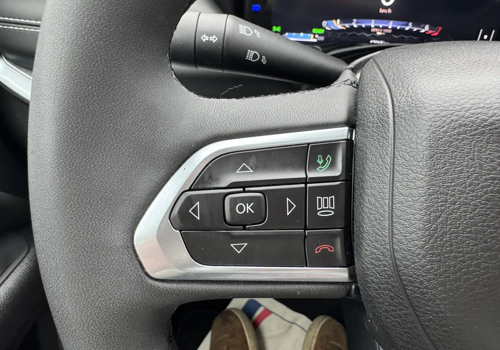 Gros plan sur les commandes du volant côté gauche du Jeep Compass gris 2023, avec boutons de navigation et appel.