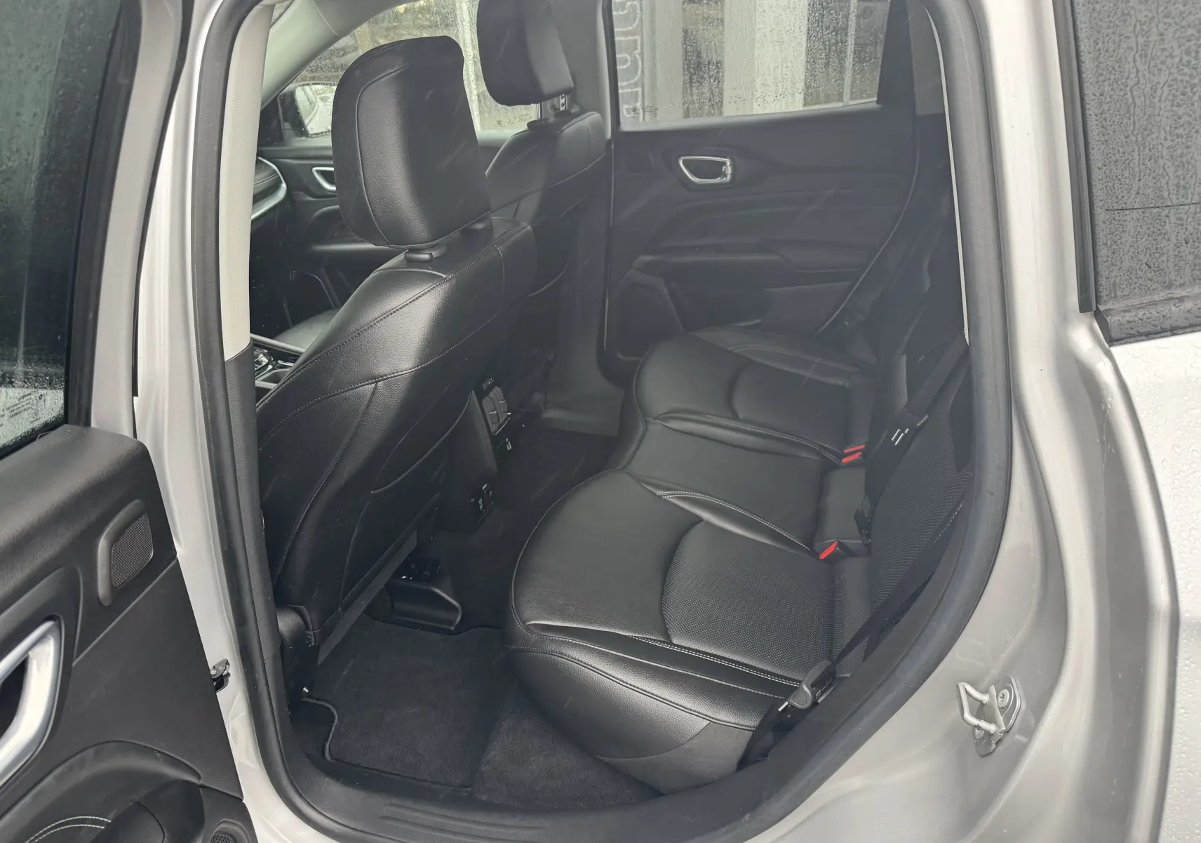 Vue intérieure côté droit sur la banquette arrière en cuir noir du Jeep Compass gris 2023, avec porte ouverte.