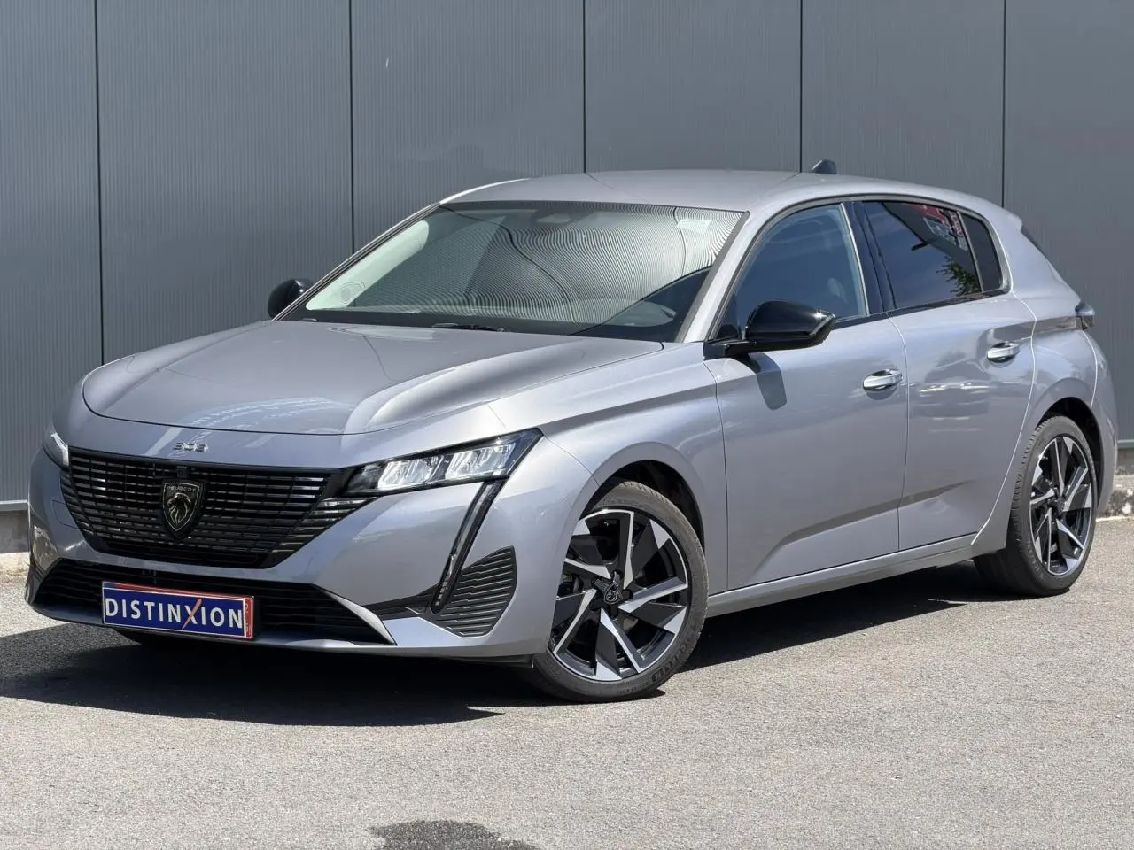 Peugeot 308 Hybrid gris Artense vue 3/4 avant droit, avec jantes alliage et signature lumineuse LED distinctive.