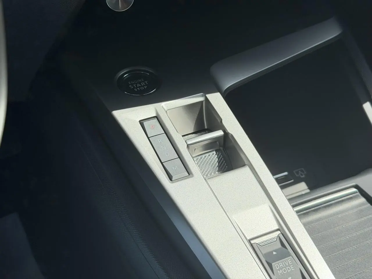 Gros plan sur la console centrale gris clair de la Peugeot 308 Hybrid avec boutons de boîte auto et bouton start/stop.