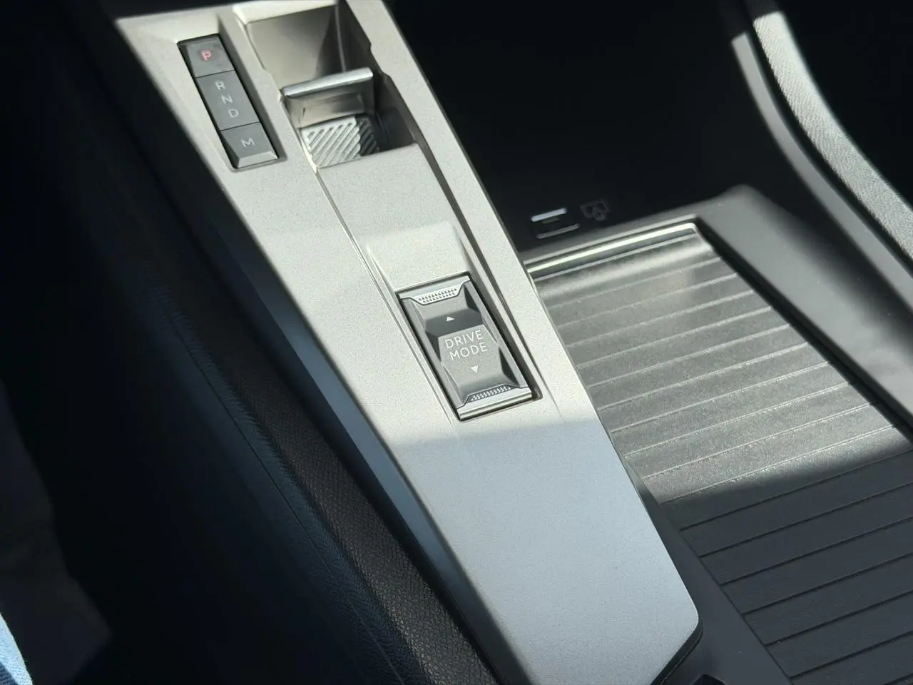 Gros plan sur la console centrale grise de la Peugeot 308 Hybrid avec sélecteur de mode de conduite et levier de vitesses automatique.
