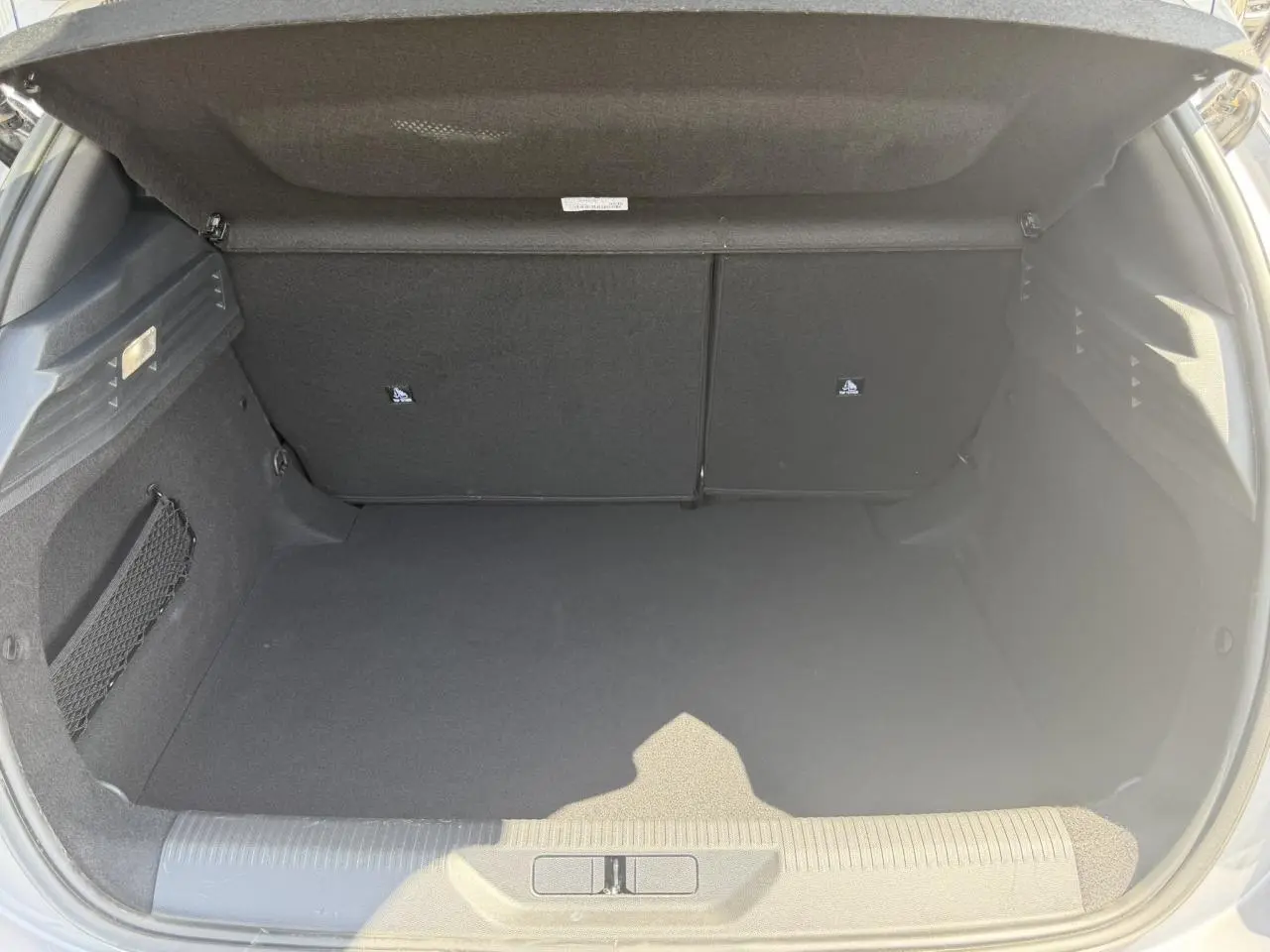 Coffre ouvert de la Peugeot 308 Hybrid 145 gris Artense, vue arrière montrant l'espace de rangement vide.