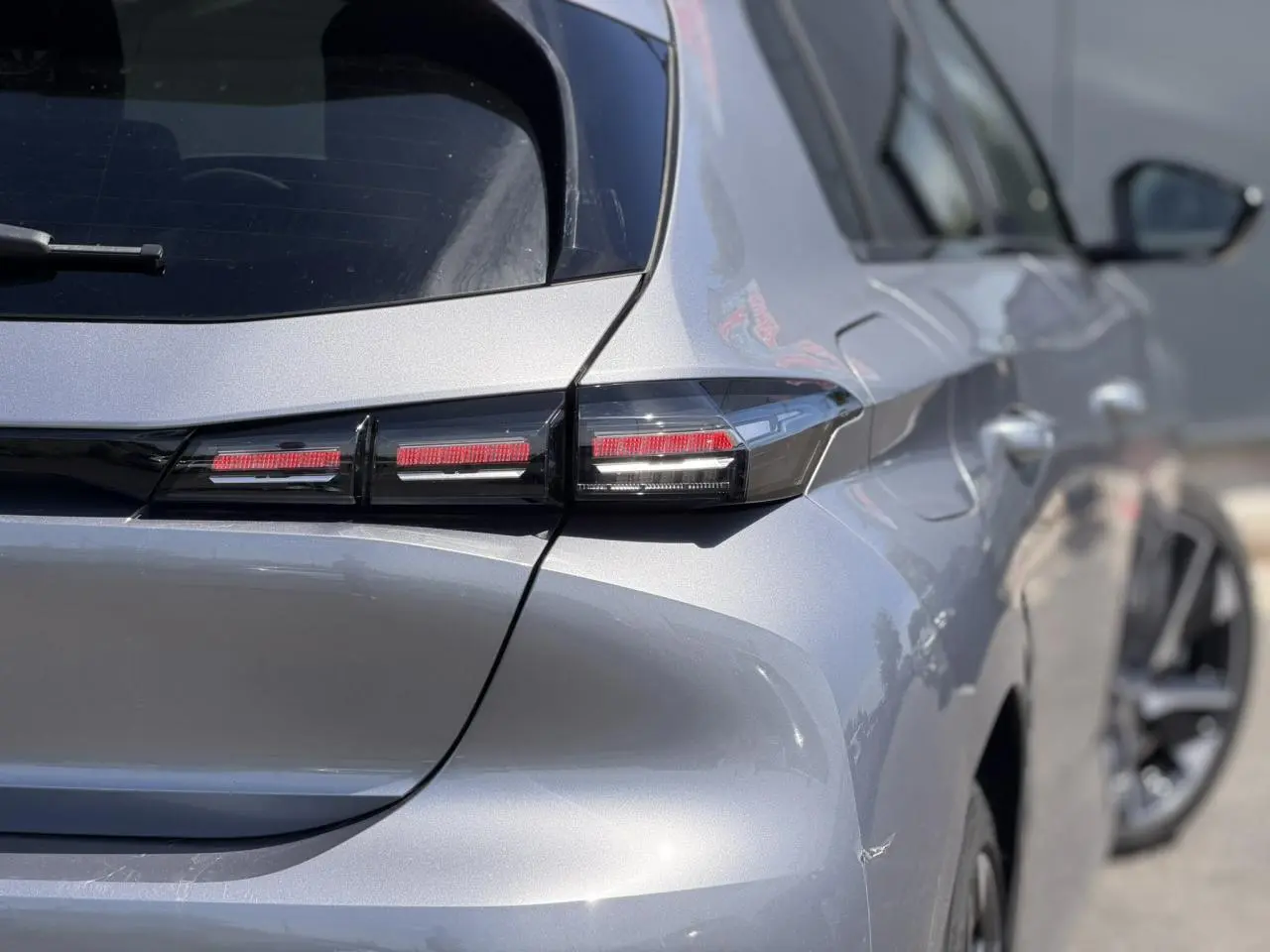 Vue arrière droite de la Peugeot 308 Hybrid 145 gris Artense, mettant en valeur ses feux arrière LED distinctifs.
