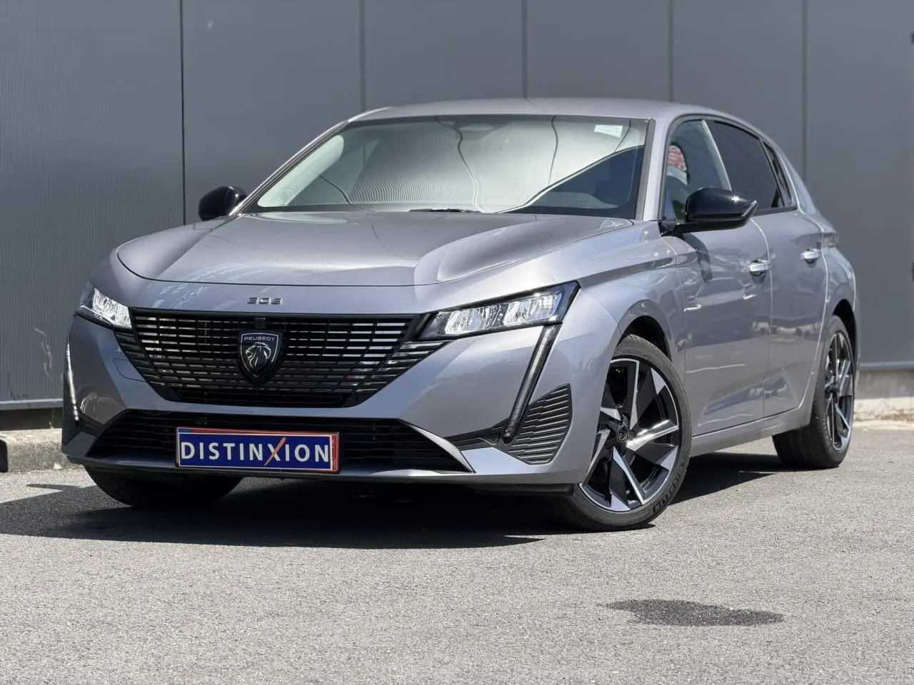 Peugeot 308 Hybrid gris Artense vue 3/4 avant droit, avec calandre noire et jantes alliage 17 pouces.