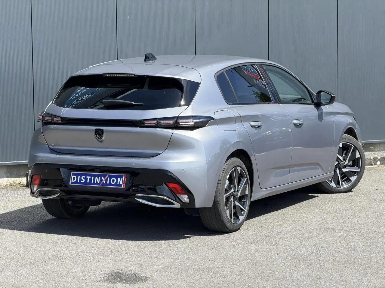 Peugeot 308 Hybrid 145 gris Artense vue 3/4 arrière droit, jantes alliage et feux arrière LED distinctifs.