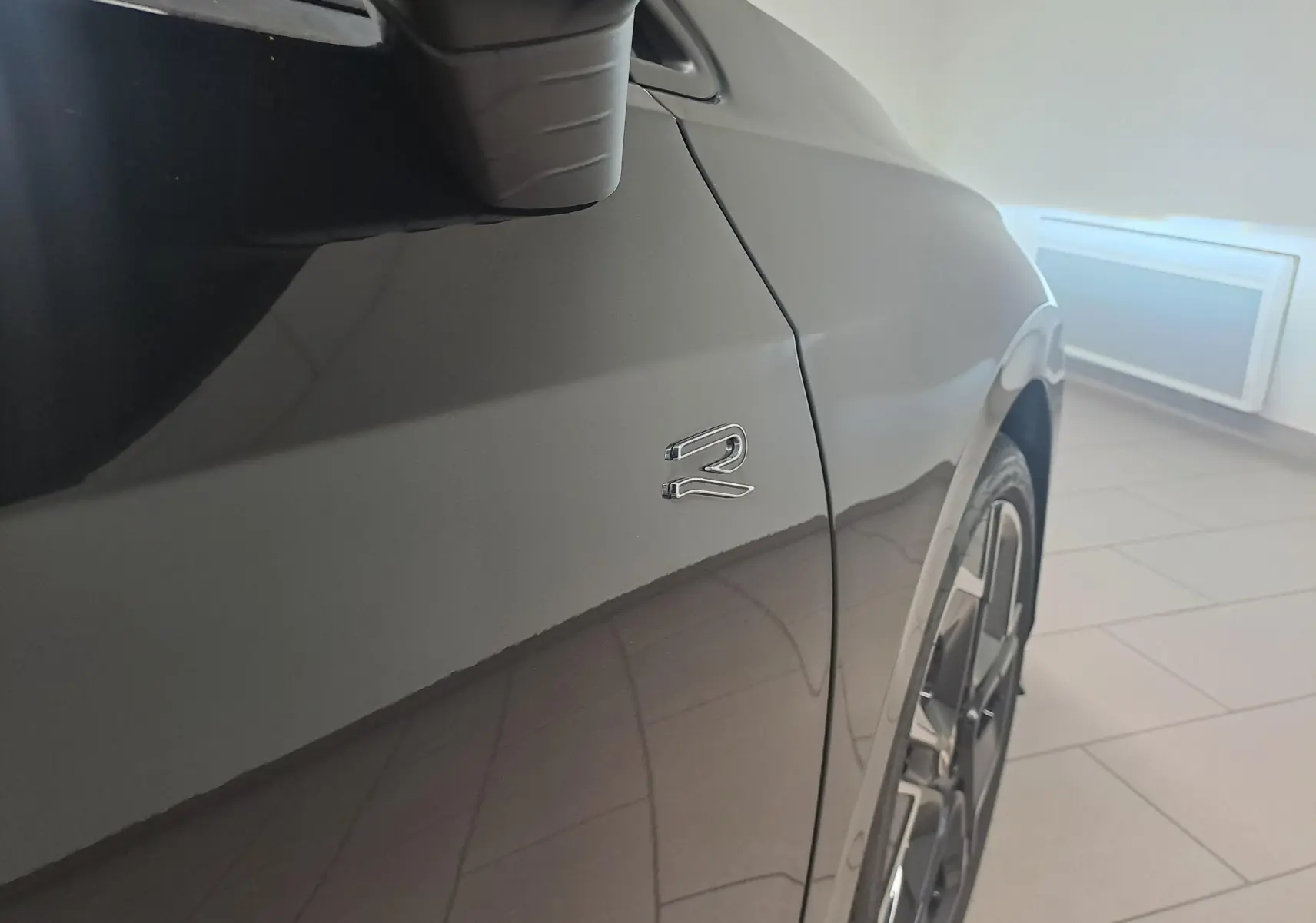 Détail du côté gauche d’une Volkswagen Golf 2.0 TDI R Line noir grenadille avec logo R et jante alliage 18 pouces.