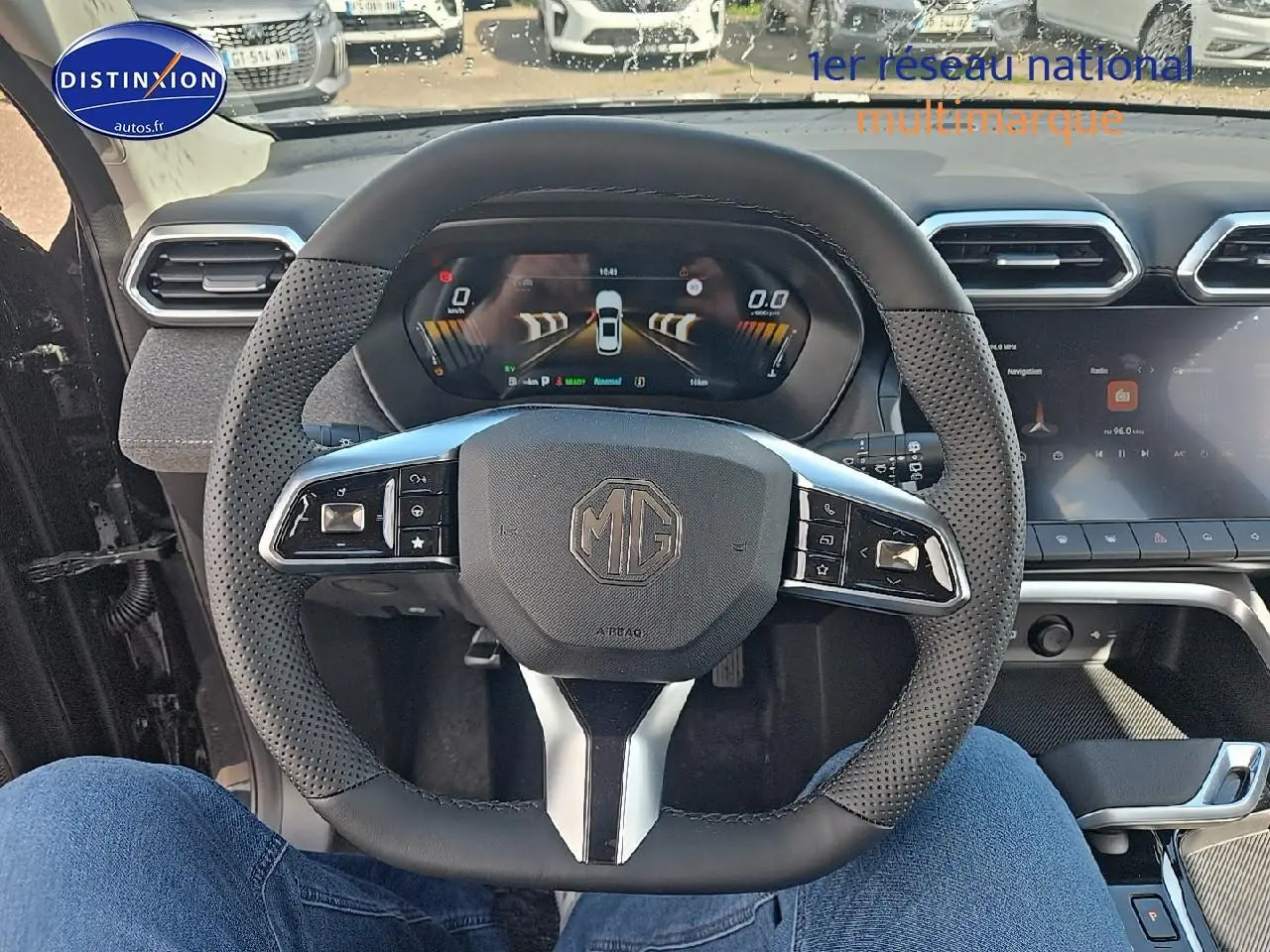 Vue intérieure centrée sur le volant noir perforé du MG ZS Hybrid 2026 avec tableau de bord numérique et écran tactile.