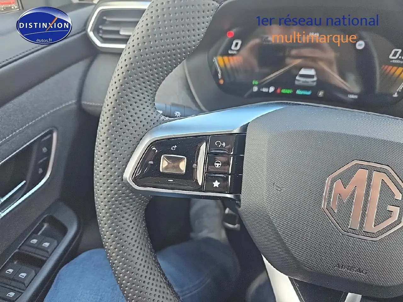 Gros plan sur le volant noir perforé du MG ZS Hybrid 2026, avec commandes intégrées et tableau de bord numérique en arrière-plan.
